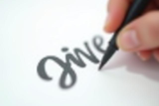 A hand demonstrates brush lettering with a flexible brush pen, creating a stylish word.