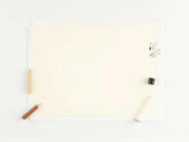 A finely arranged beginner's calligraphy kit with an inkwell, several nibs, a pen holder, and high-quality paper, ready to use.